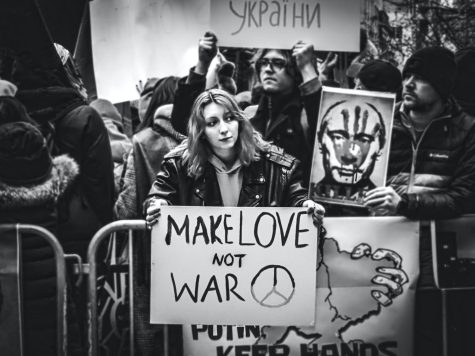 Woman holding sign saying Make Love Not War in New York, USA
